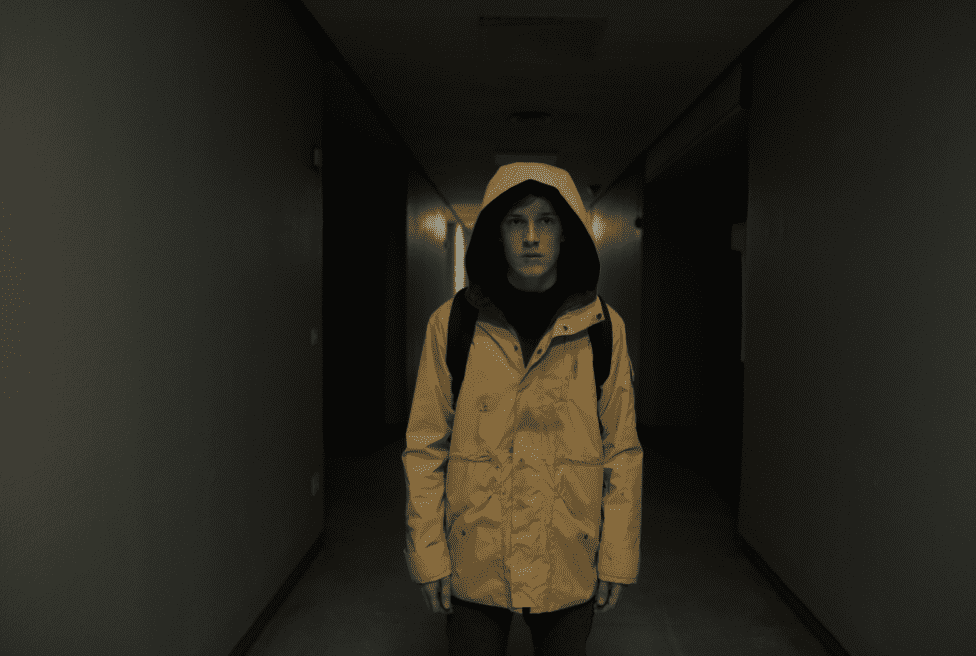 A child in a bright yellow raincoat standing in a dark hallway