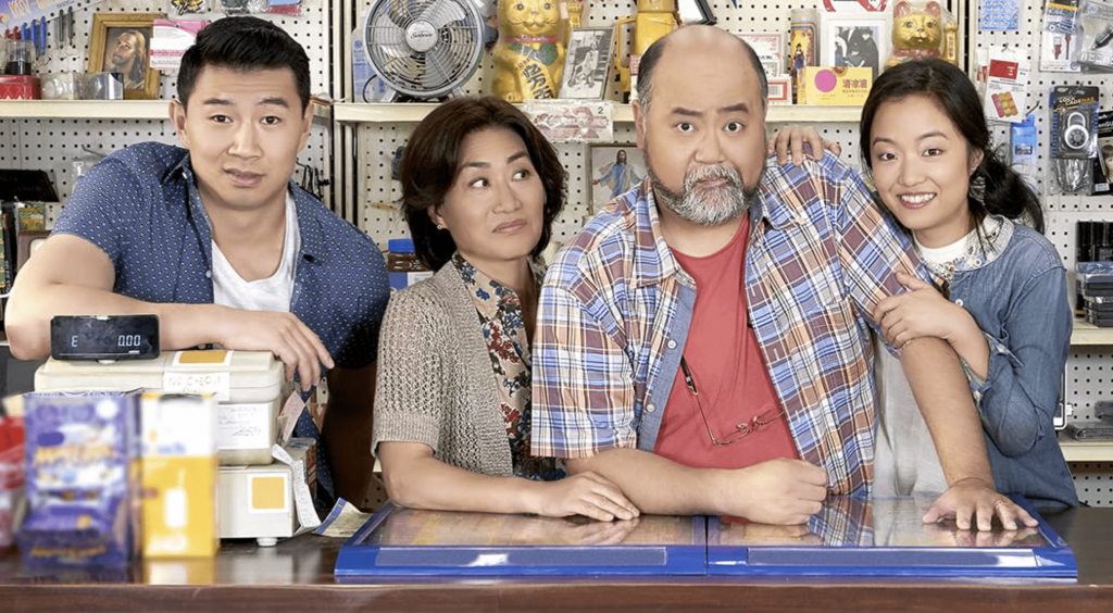 The main cast of the show Kim's Convenience standing behind the counter of their Toronto bodega