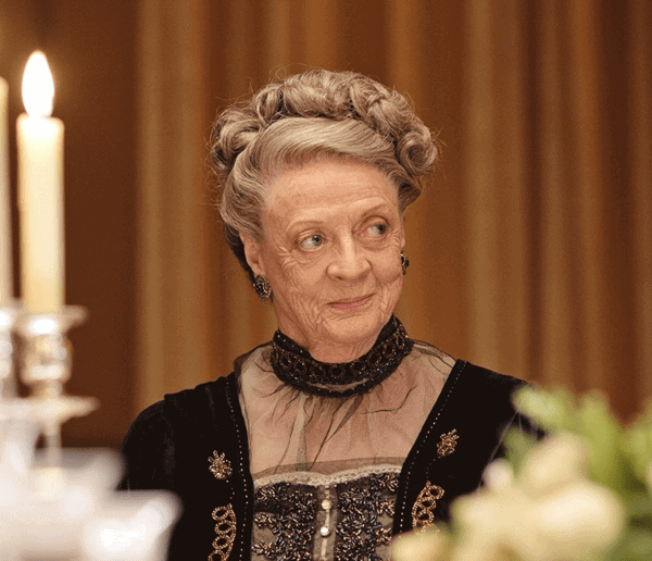 An old woman smiles while wearing a black vintage dress in this image from Carnival Films.