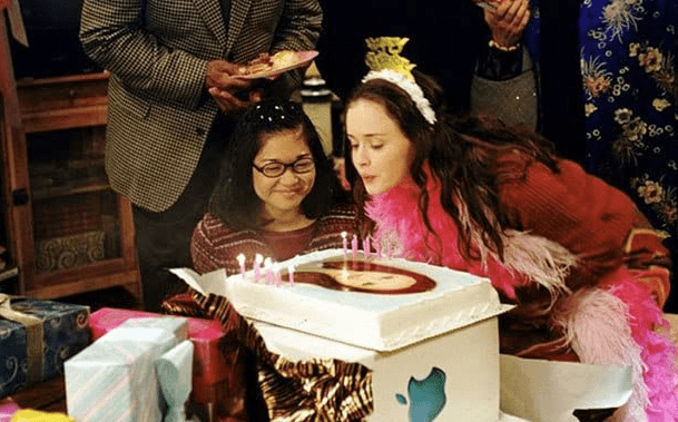 Two young girls celebrate a birthday with cake in this image from Warner Bros. Television.
