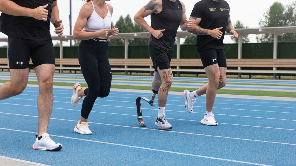 Four runners, including one wearing a prosthetic leg, sprint along the track in this image from Shutterstock
