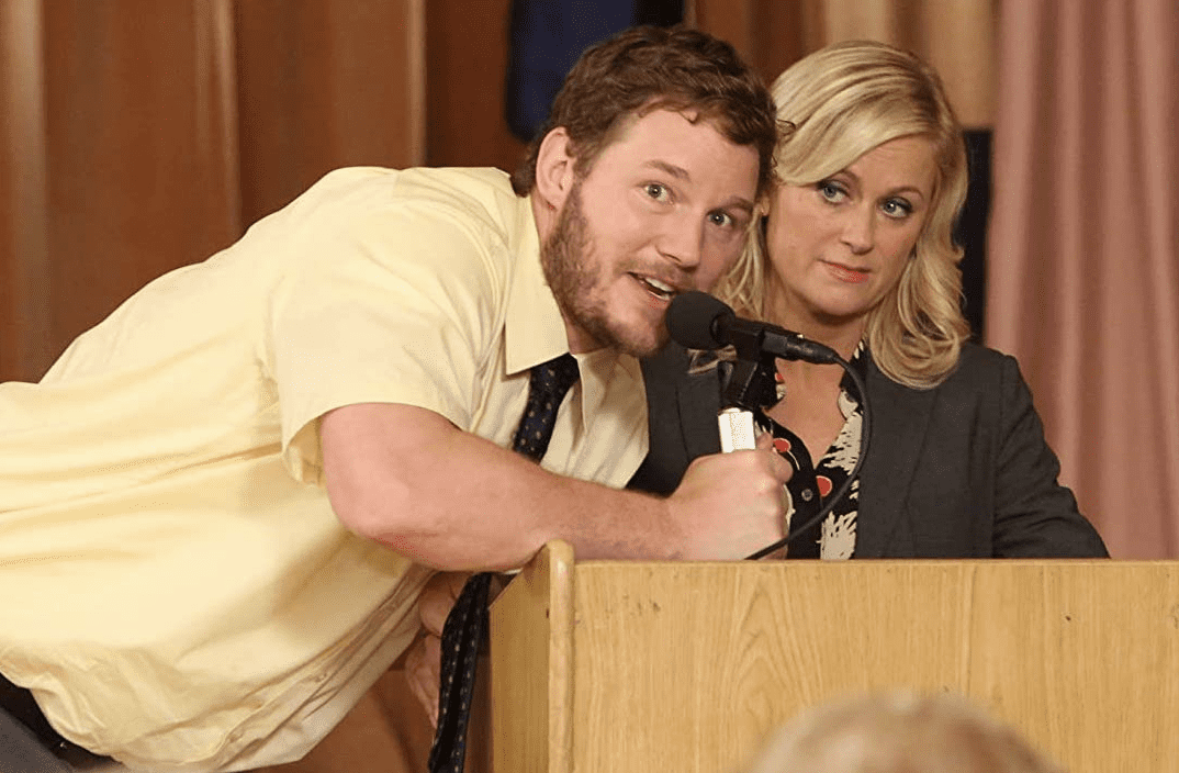 A man takes a microphone from a woman at a podium in this image from Deedle-Dee Productions.