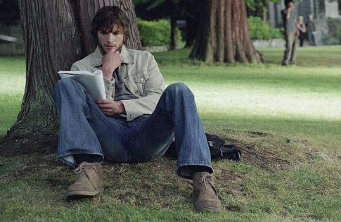 Evan sitting against a tree with a journal in hand