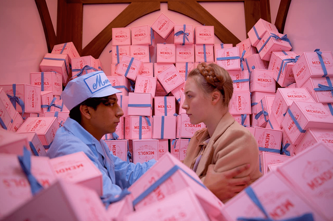 A young man and woman in a pile of pink boxes in this image from Fox Searchlight Pictures.