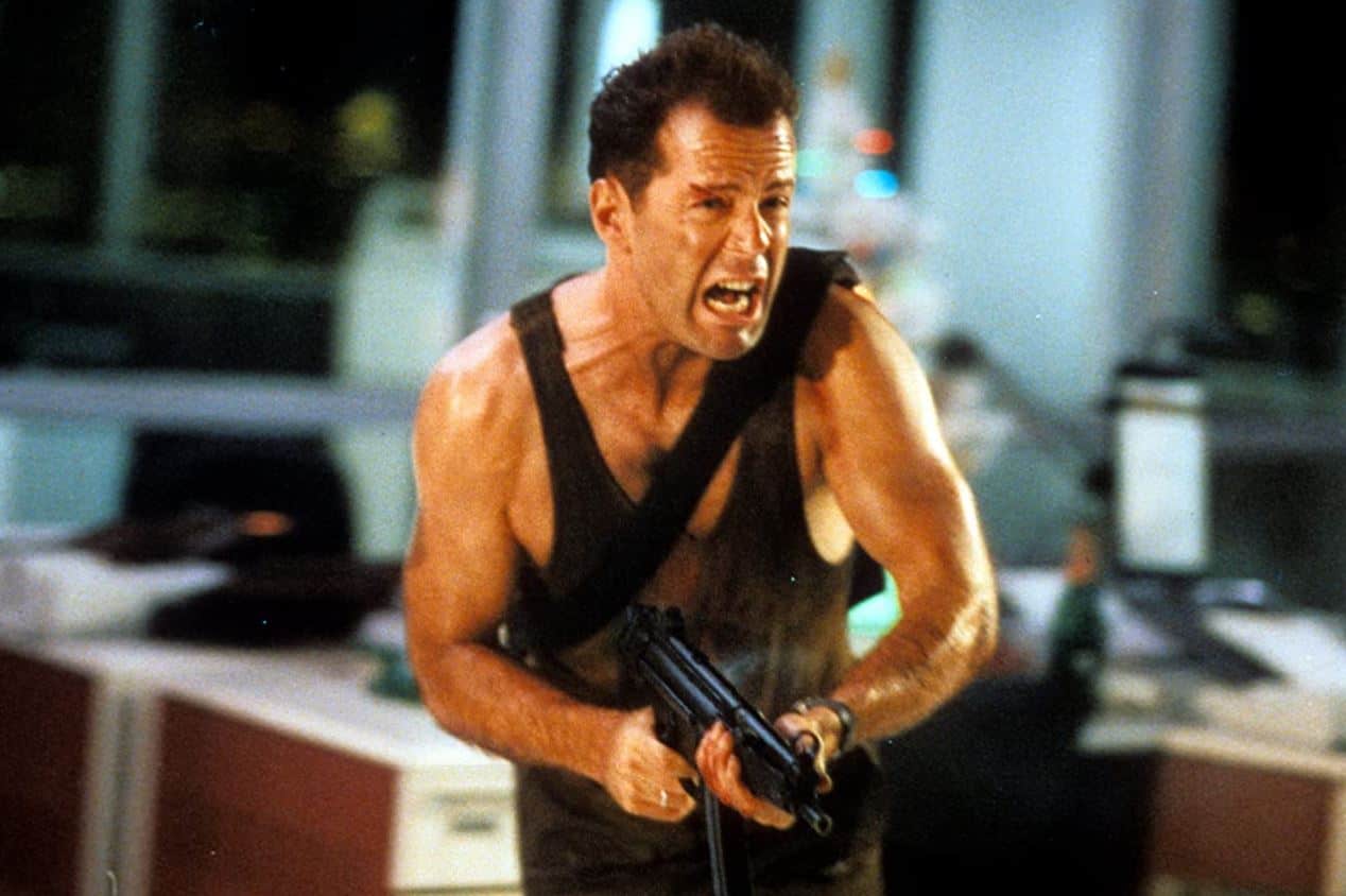 John McClane charging through an office with a gun