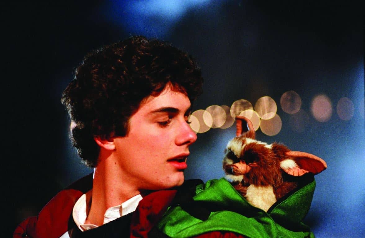 Billy looks at his pet mogwai, Gizmo, in a green backpack.