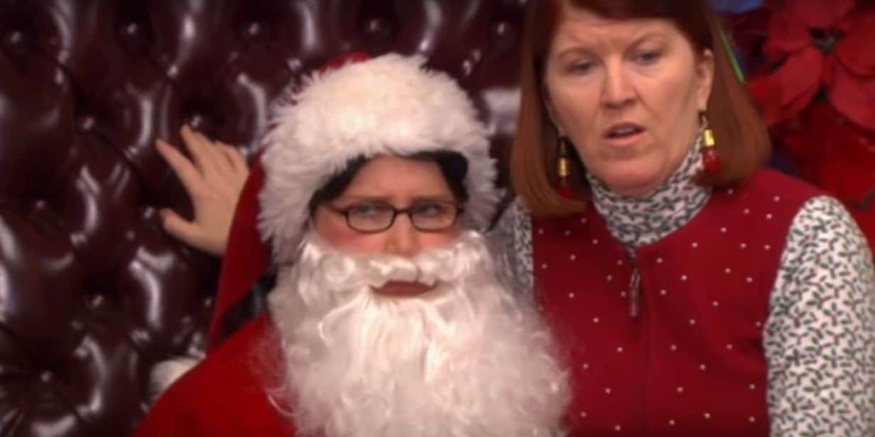 Meredith sits on a Santa-dressed Phyllis.