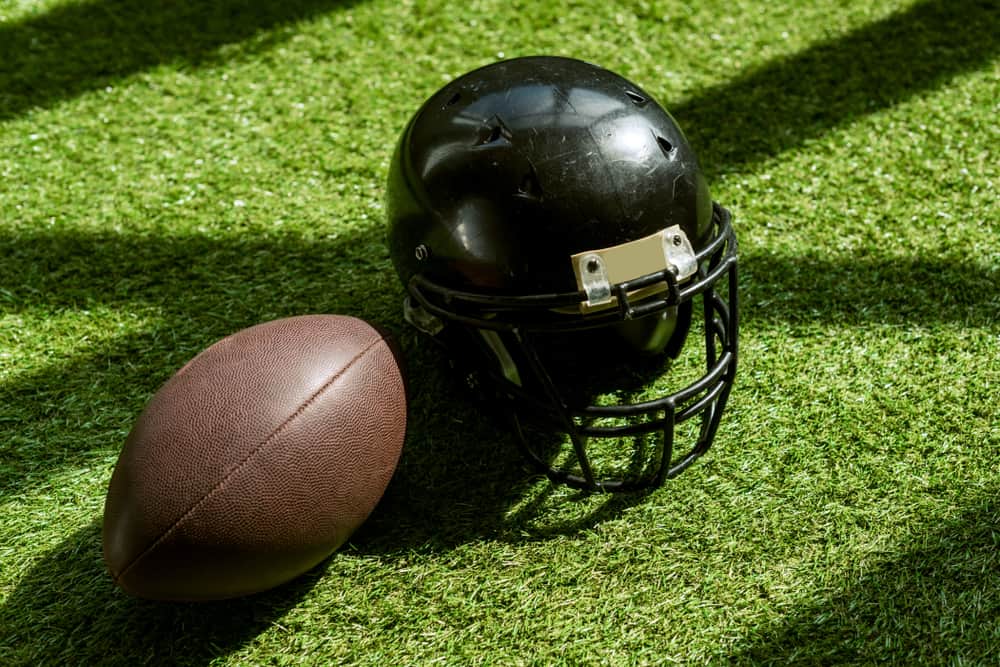 Football and football helmet on a green field