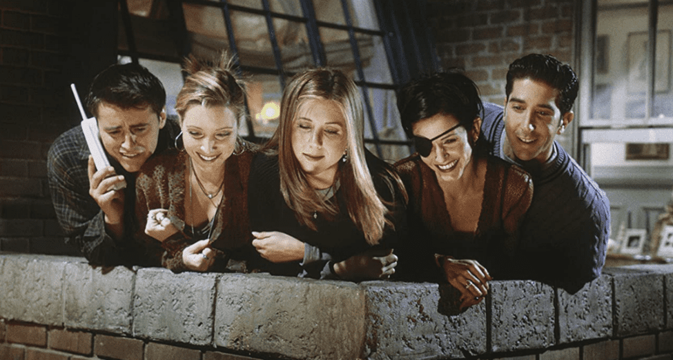 The cast of “Friends” leaning over the rooftop balcony