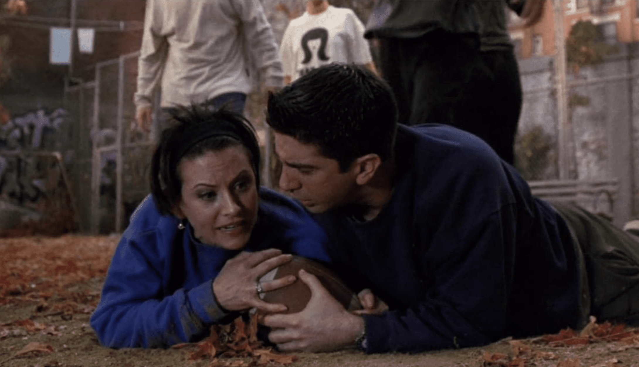 Sibling rivalry gets the best of Monica and Ross, who lay on the ground fighting for a football.
