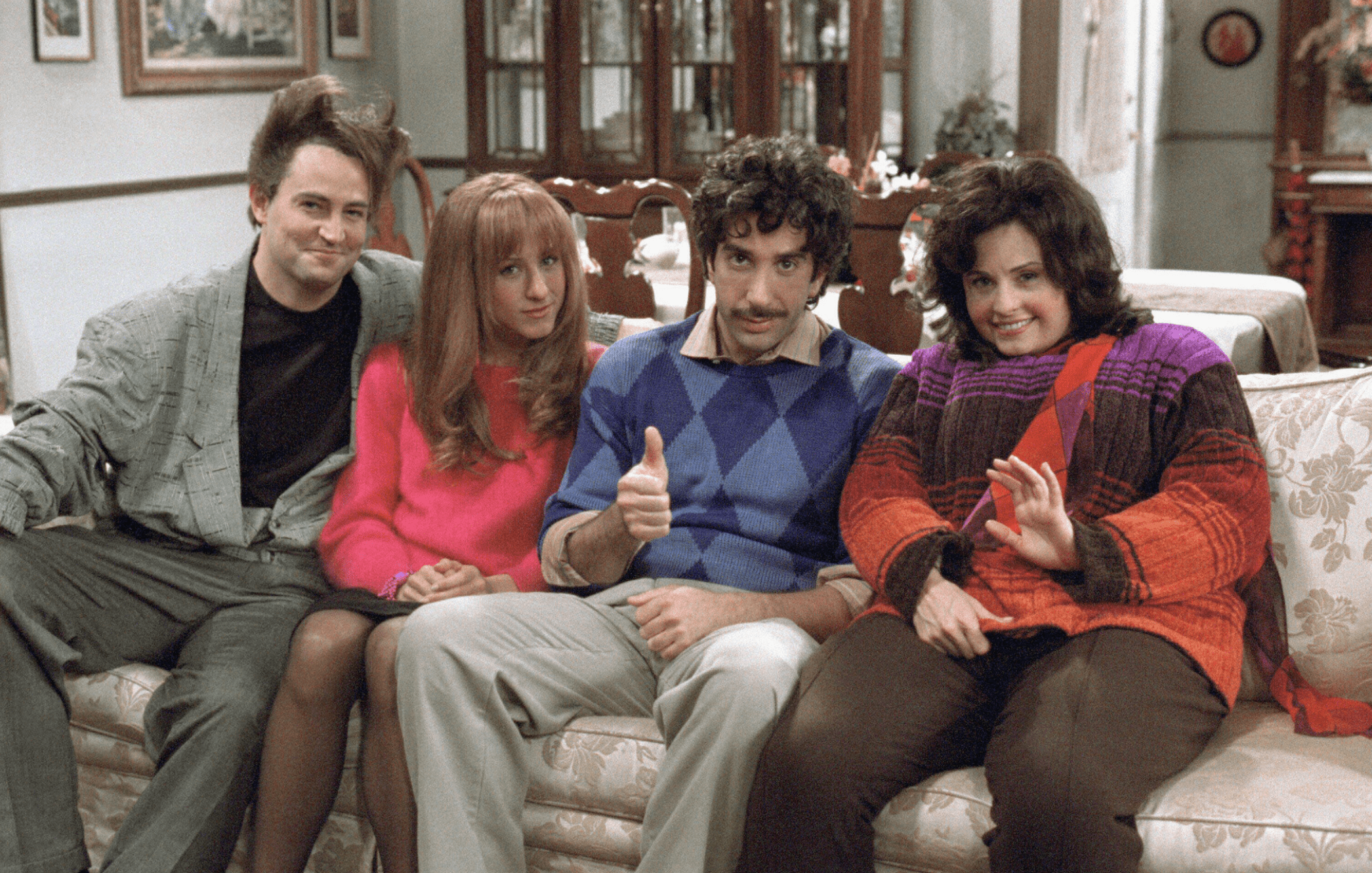 Chandler, Rachel, and the Gellers sit on a couch at the Geller home.