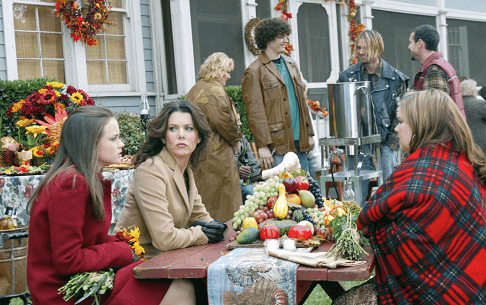The cast of “Gilmore Girls” sitting around a picnic table