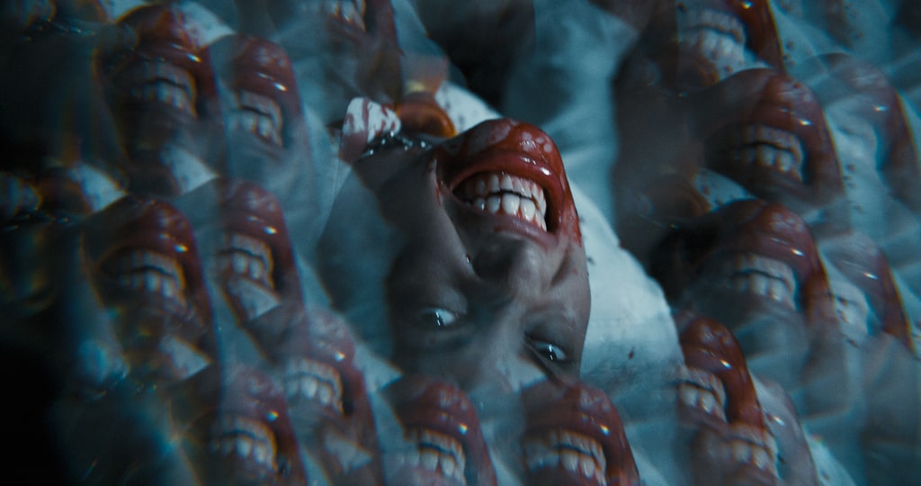 A kaleidoscope view of a woman with a bloody mouth who’s upside down in this photo from Divide/Conquer