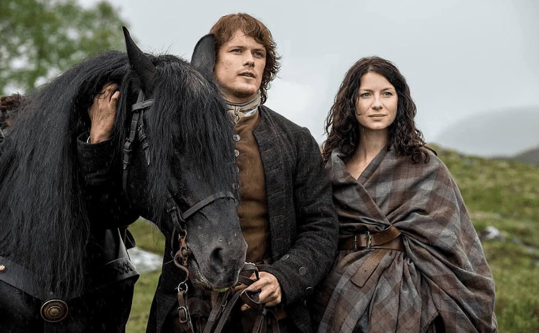 Sam Heughan and Caitríona Balfe with a black horse