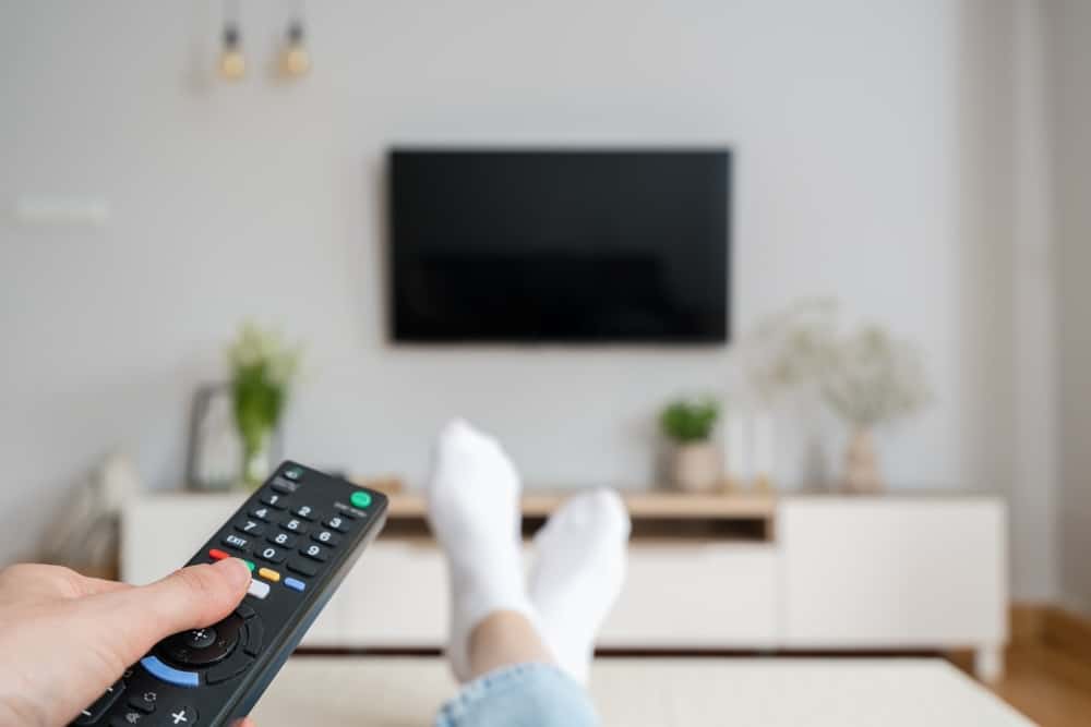 A hand holding a remote to turn on the TV