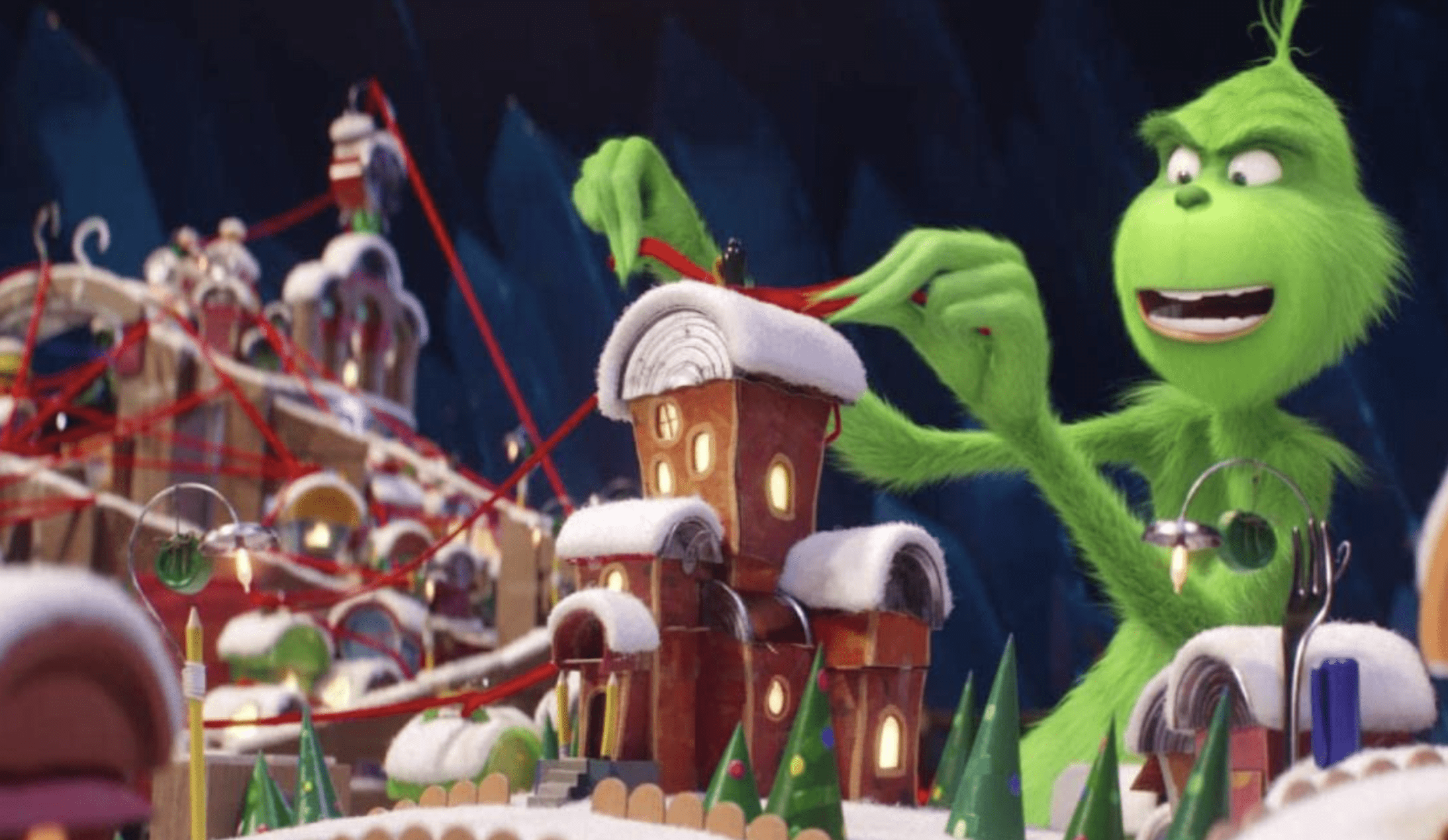 The Grinch plays with a red string on a homemade map of Whoville.