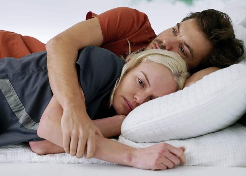 Mike and Kate lying on a bed in an all-white room