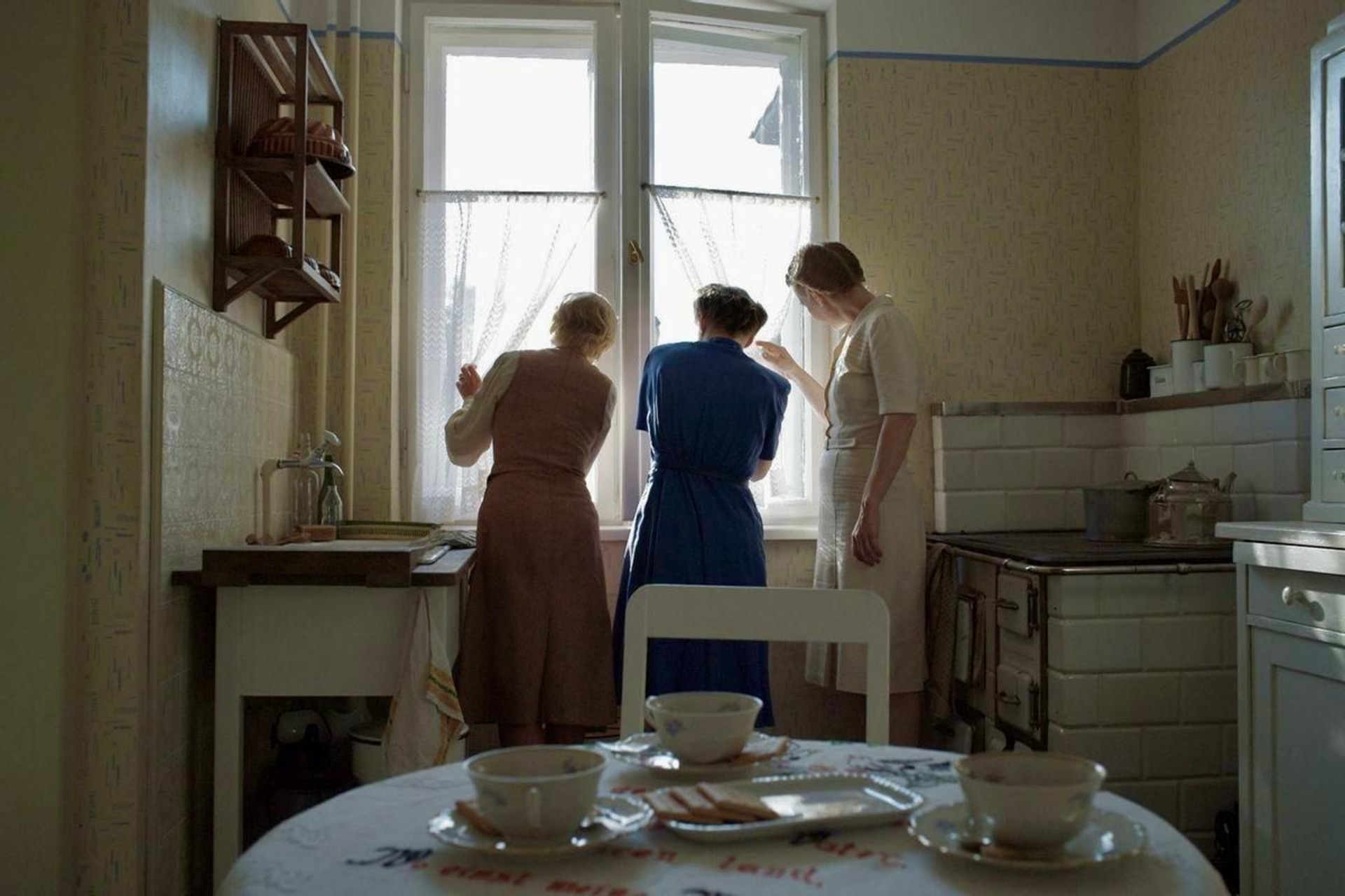 Three maids look out a window in this image from A24.
