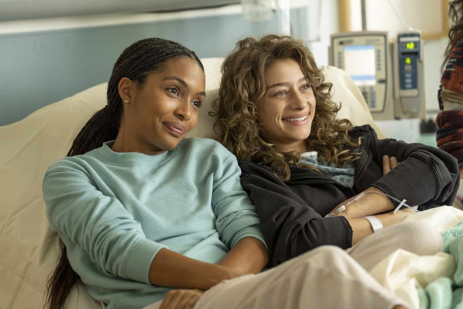 Two women sharing a hospital bed while smiling in this photo from Amazon Studios