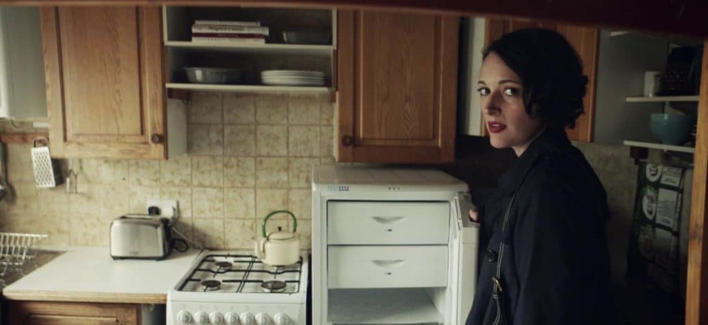 Fleabag standing in a kitchen and breaking the fourth wall