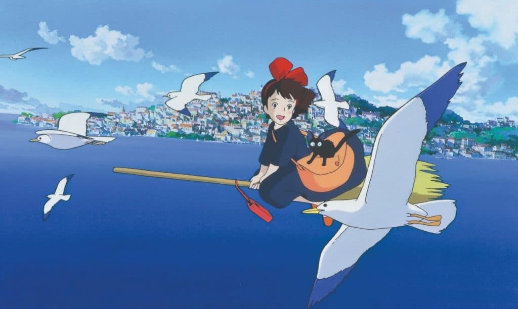 Kiki and Jiji flying on a broom over the ocean with a flock of seagulls