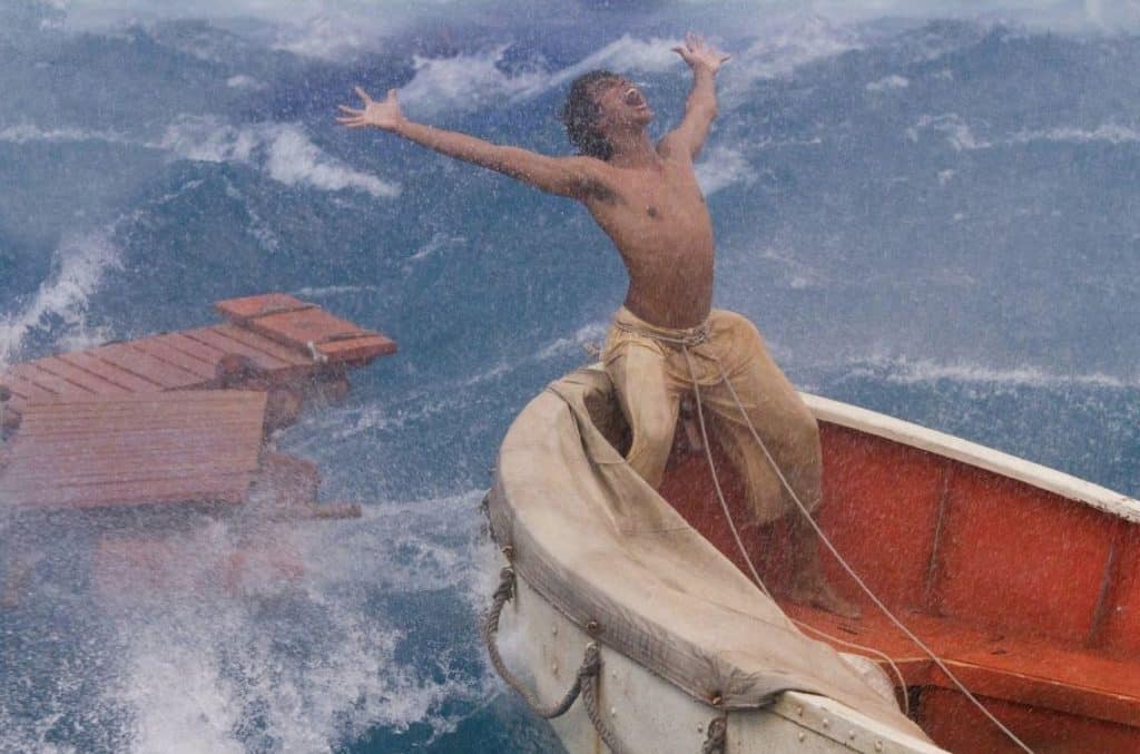 Pi Patel on a lifeboat in a stormy ocean, opening his arms to the sky