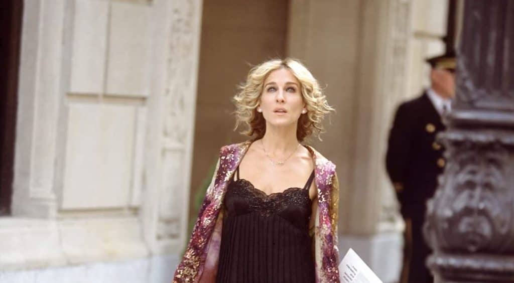 Carrie Bradshaw in a chic dress with short, curly hair