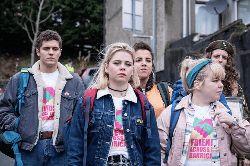 The main cast of “Derry Girls” wearing shirts that read “Friends Across the Barricade”