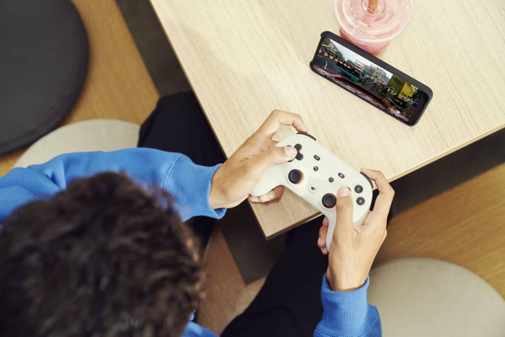 A person playing a game on a smartphone with a Google Stadia controller