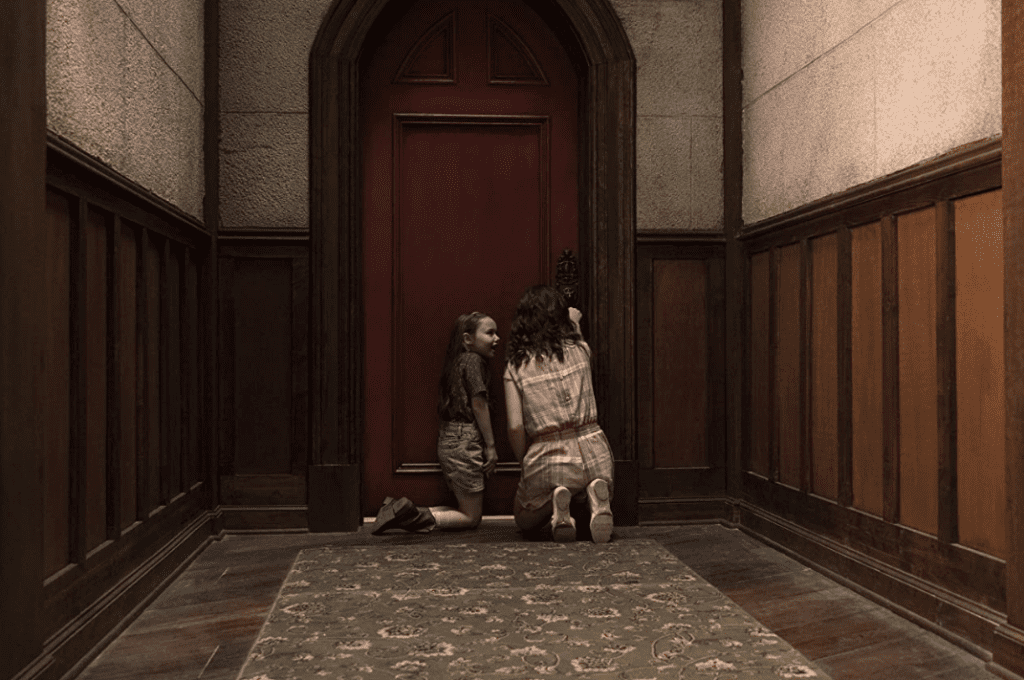 Two young girls kneel in front of a door in this image from Paramount Television.