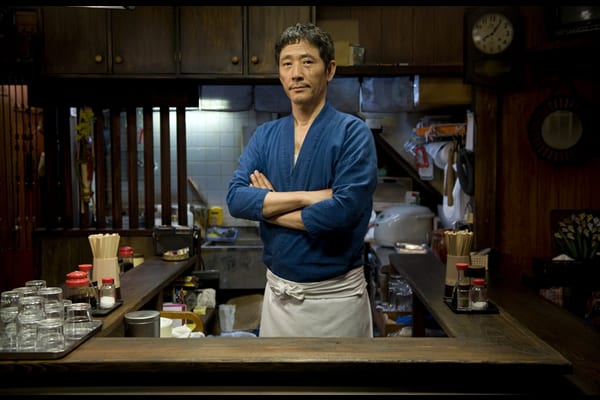 Master standing behind his diner counter with crossed arms