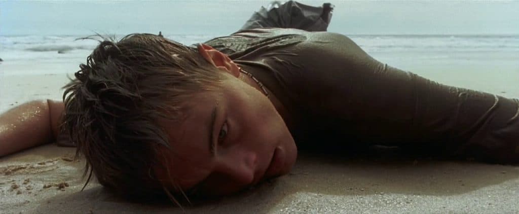 Richard lying facedown on a beach, soaking wet