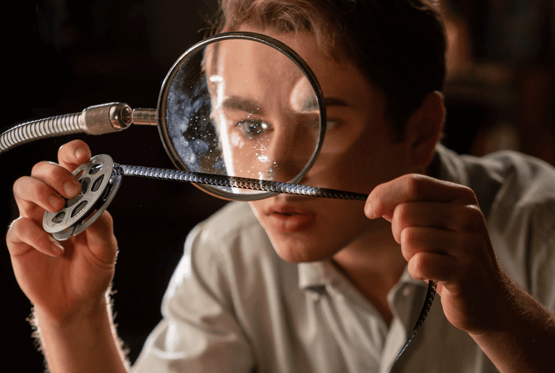 Sammy examining a roll of film through a magnifying glass