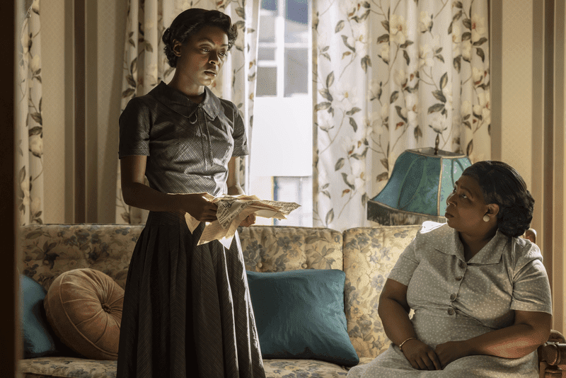 Mamie holding newspaper clippings and talking to Alma