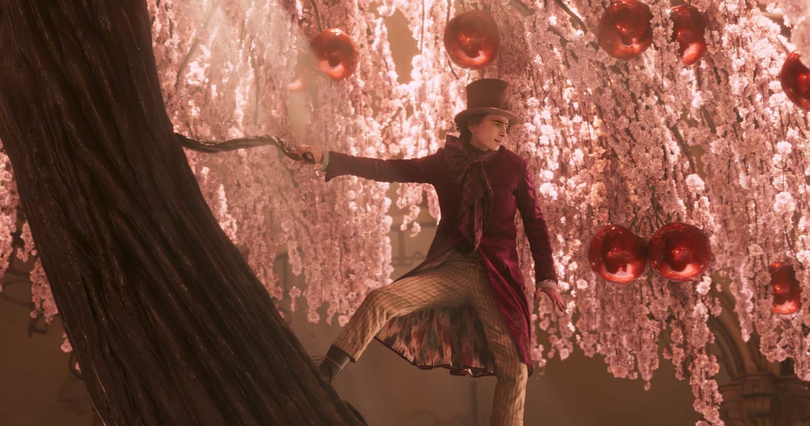 A man in a tophat clinging to a tree with giant cherries in this image from Warner Bros.