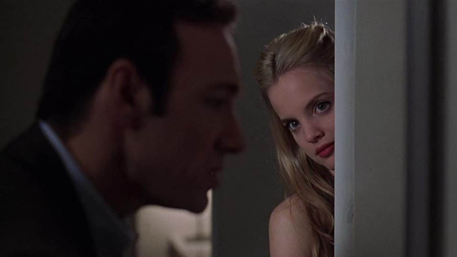 Angela Hayes peeks around a wall to look at Lester Burnham