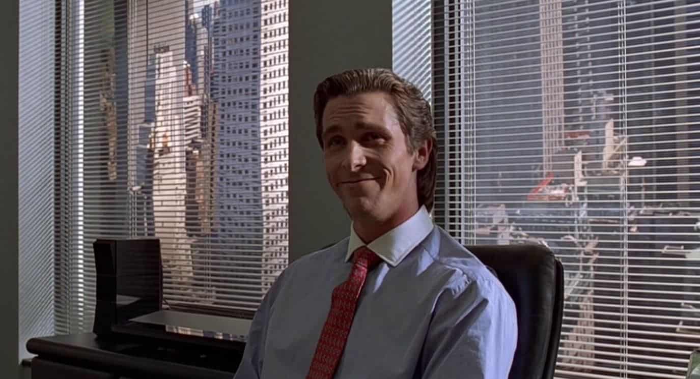 Patrick Bateman smiles painfully in his high-rise office on Wall Street.