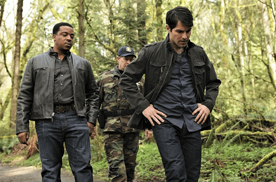 Hank and Nick walk through the forest to a crime scene.