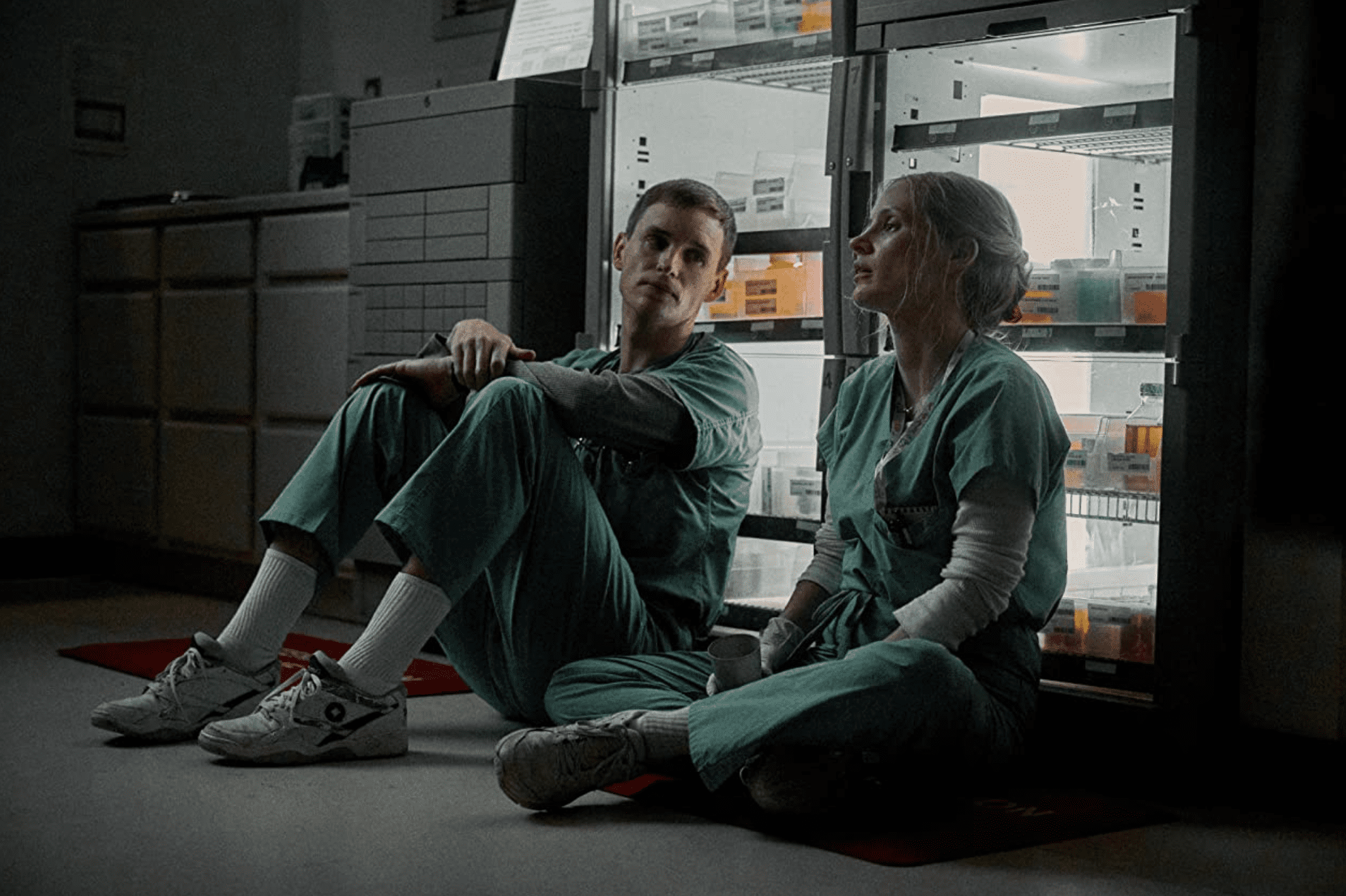 Charlie and Amy sit on the floor together in the medication storage room