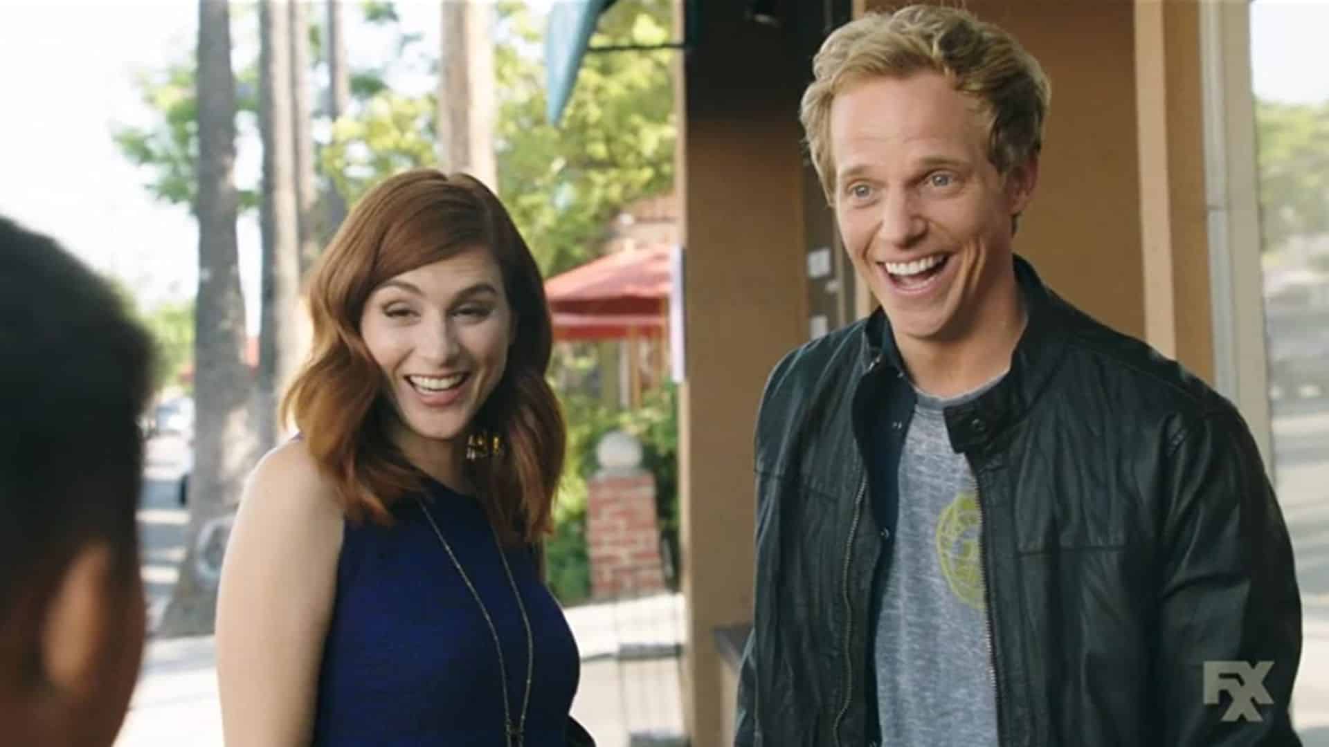 A woman with red hair and a man with blond hair react to someone off-screen in this image from FX Productions.