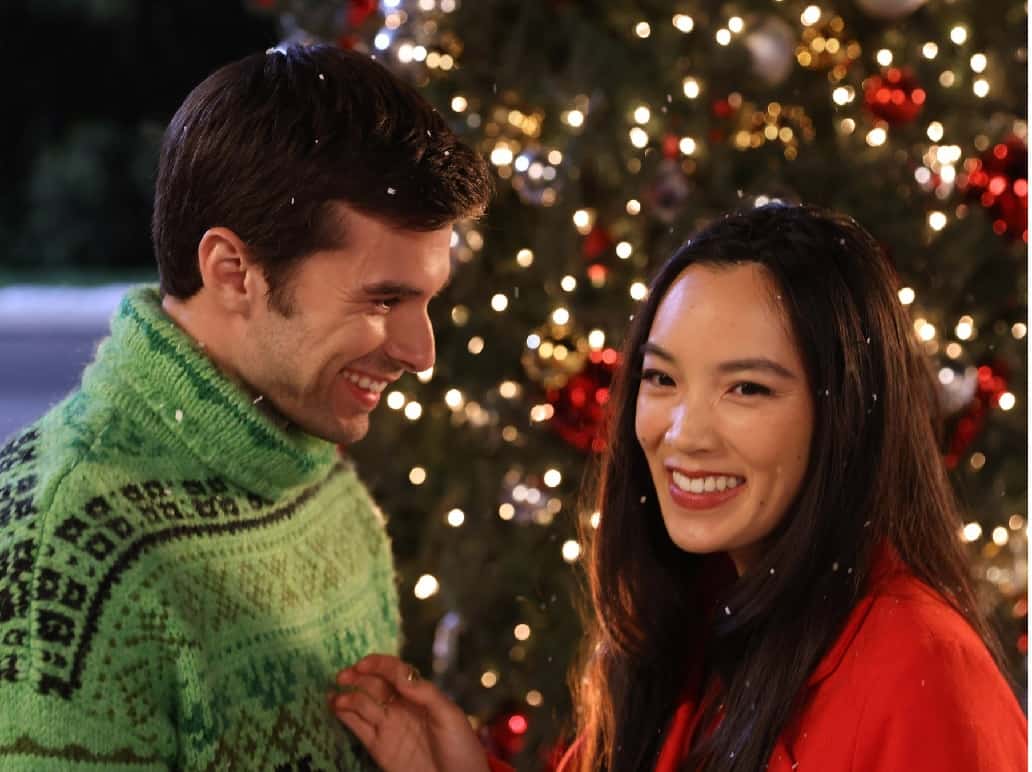 Christopher and Jessica smiling in front of a Christmas tree