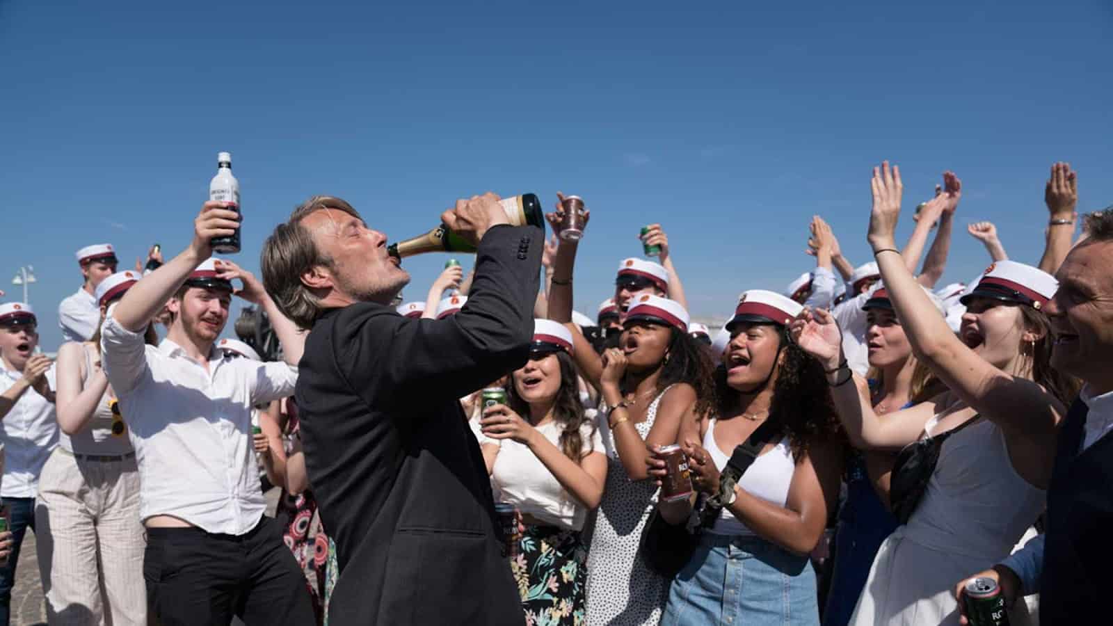 Martin drinking champagne from a bottle in front of a cheering crowd