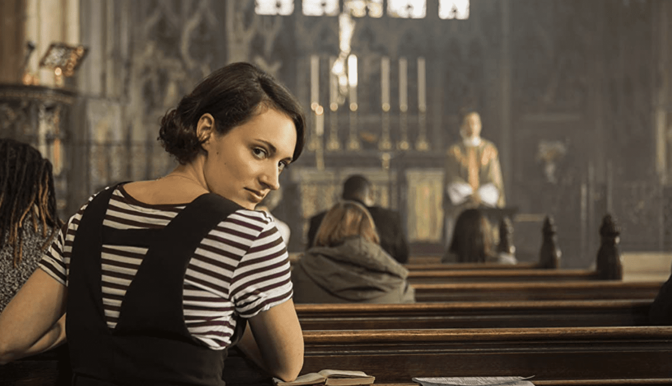 A woman kneeling at a church looks over her shoulder at the camera while the church altar looms softly out of focus in the background