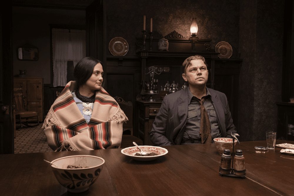 Mollie in native dress and Ernest in a suit side by side at a dining table