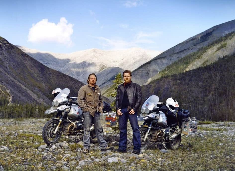 Charley and Ewan posing in front of dramatic mountain scenery with their motorcycles