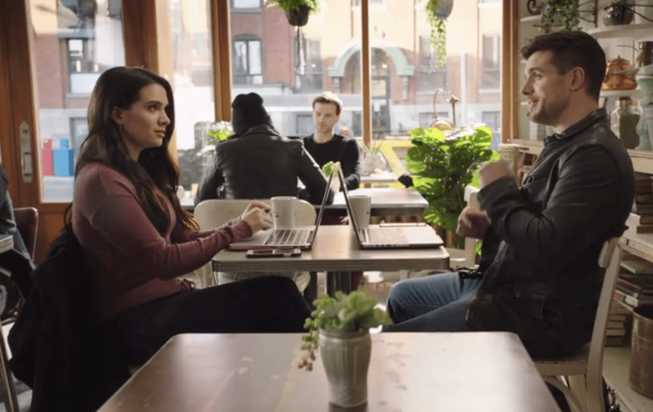 Jane and Ryan sit together in a cafe working on a story