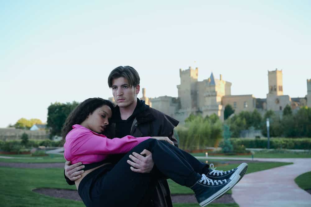 Dimitri carrying a sleeping Rose in front of old campus buildings