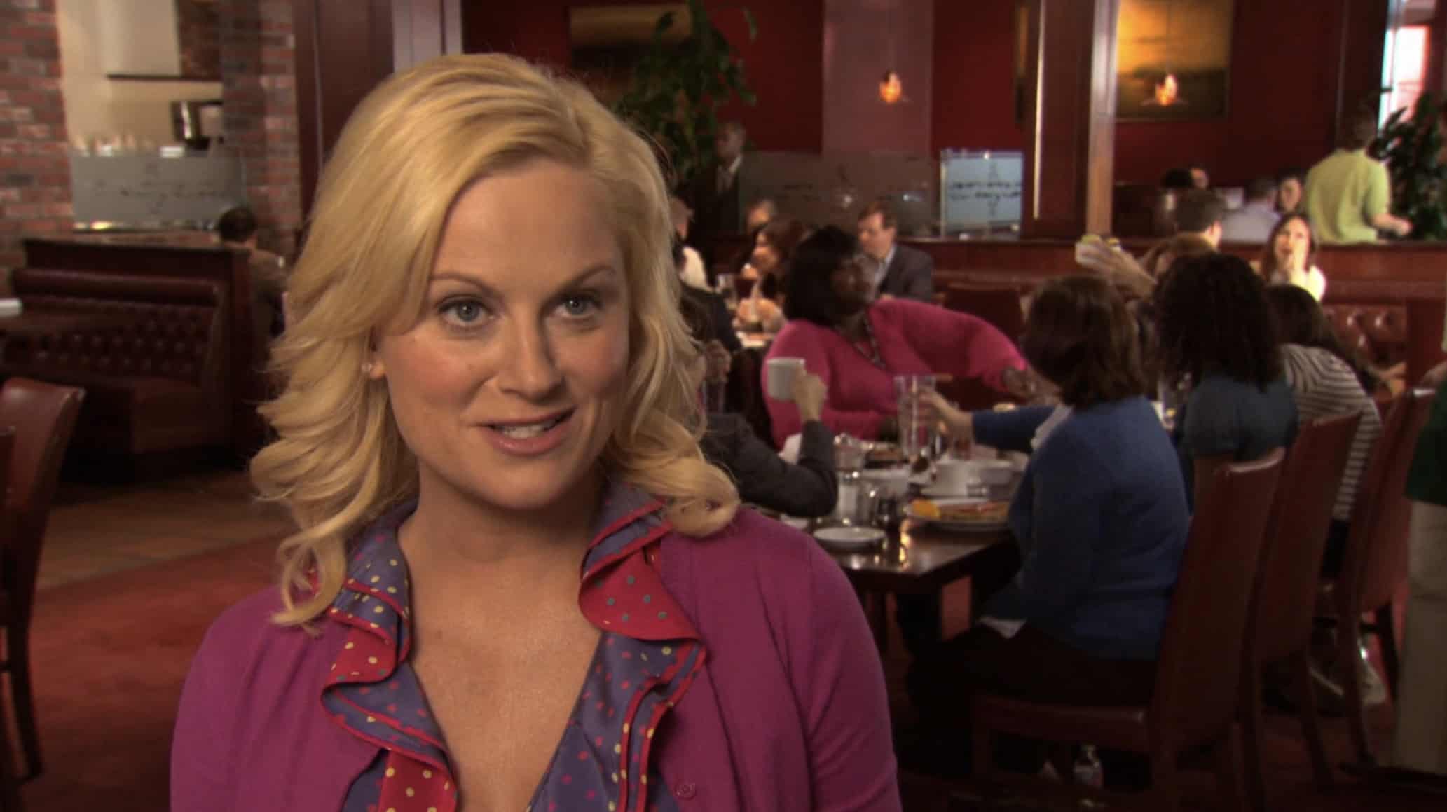 A blonde woman talks to the camera while in a restaurant in this image from Peacock