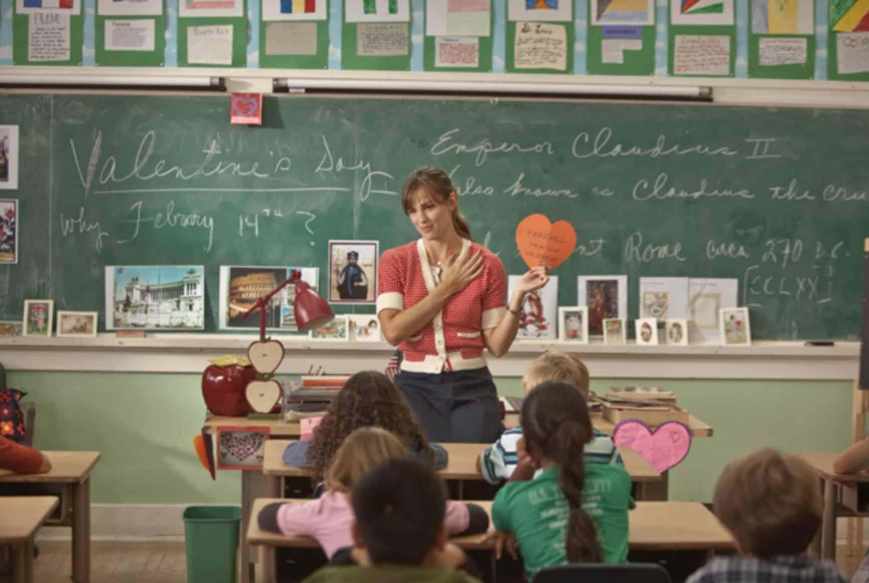 A teacher stands in front of an elementary class, holding a paper heart in this image from Amazon Prime Video