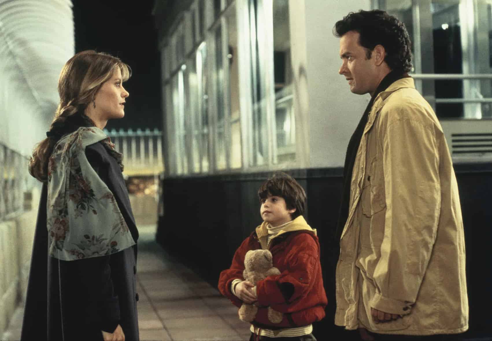 A woman, a young boy holding a teddy bear, and a man stand together in this image from Amazon Prime Video. 